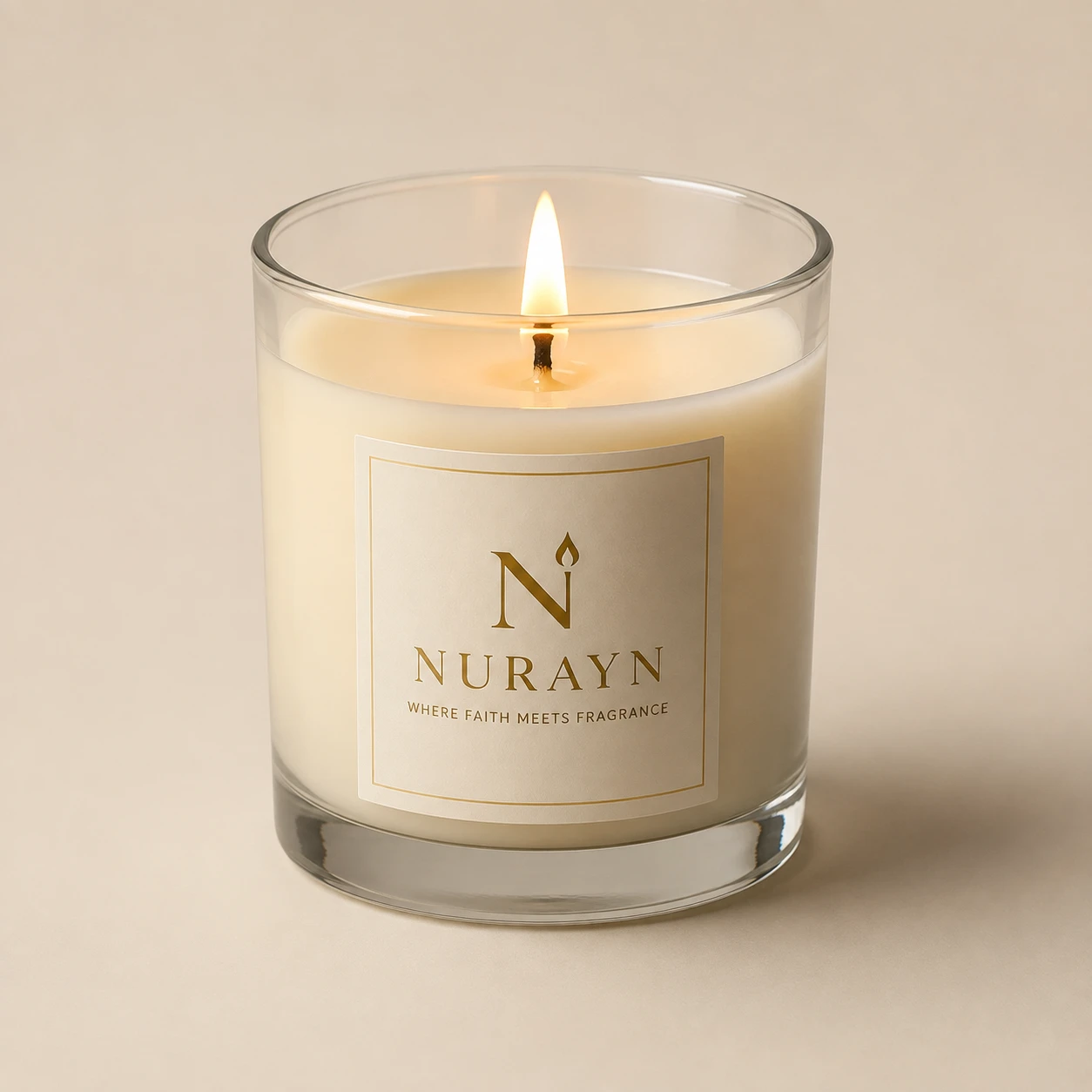 A lit NURAYN soy candle in a clear glass jar with the gold foil label